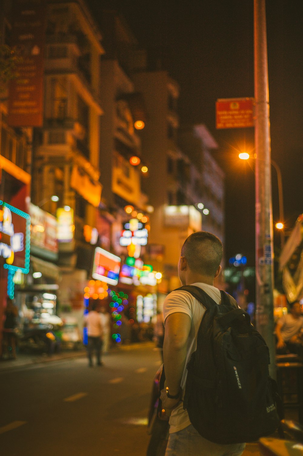 man in grey and white t-shirt standing near lamp post