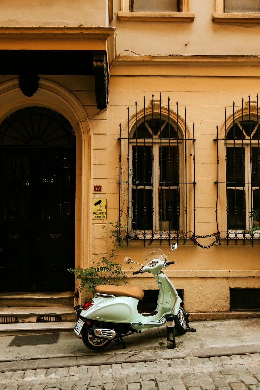 teal motor scooter parked near building