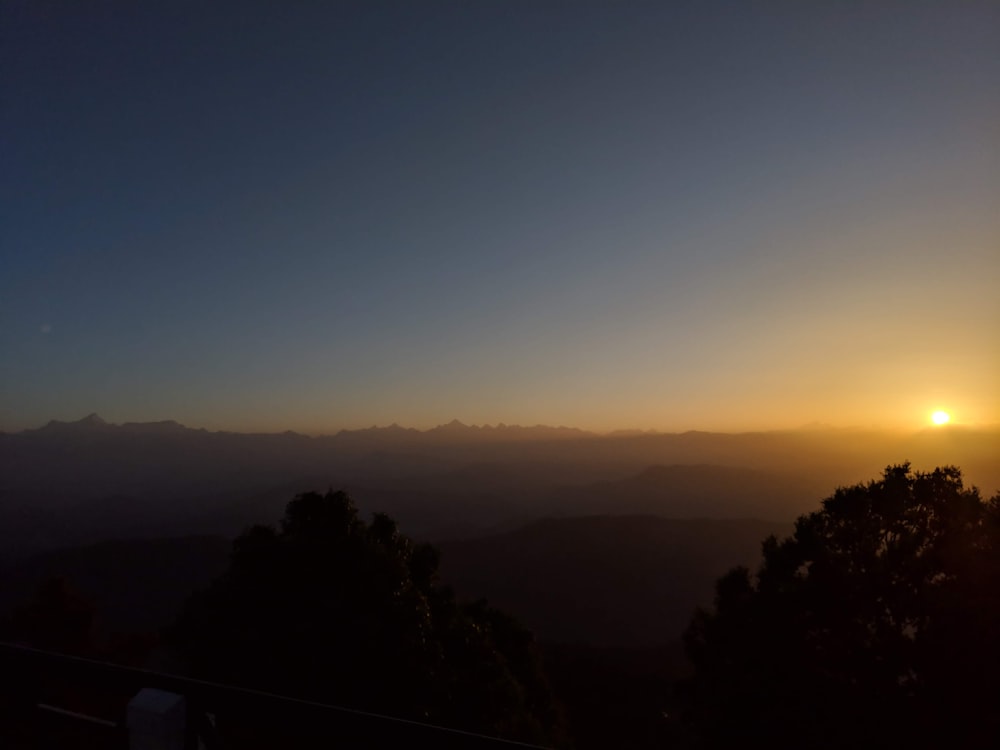 the sun is setting over a mountain range