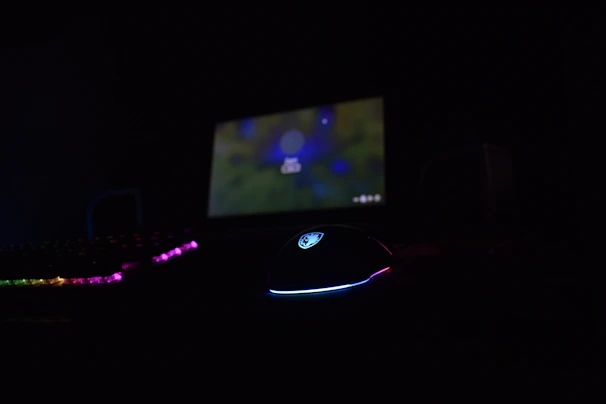 Gaming device setup with illuminated keyboard and mouse on a dark desk.
