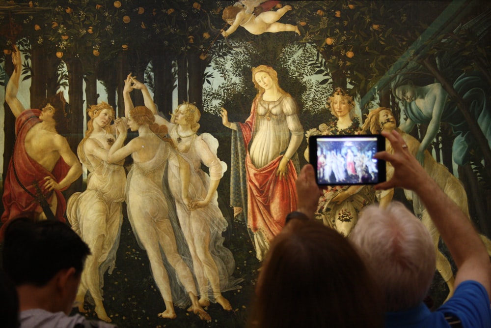 person taking a picture of a dancing women and men painting