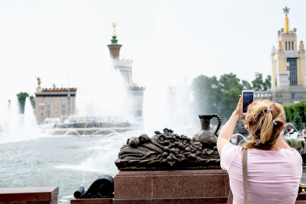 woman taking photo of water fountain