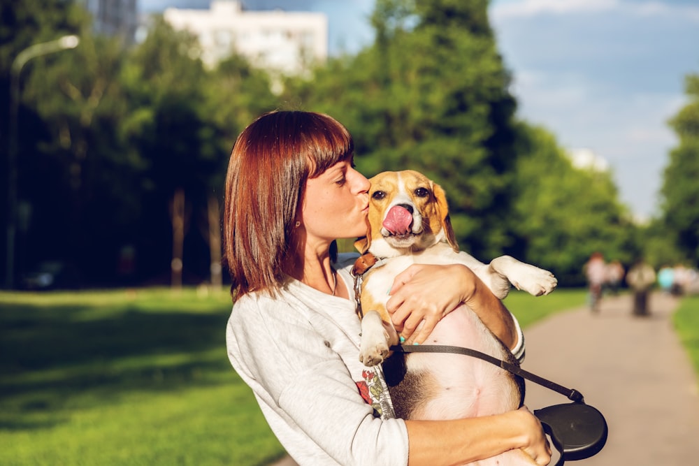 woman carrying and kissing dog