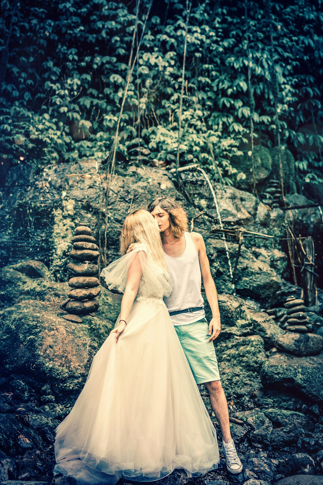 two kissing couple standing in front of stack stones