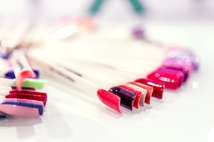 A selection of colorful nail polish samples displayed on a white surface. The colors include shades of red, pink, purple, and metallic tones, arranged neatly in a fan-like formation.