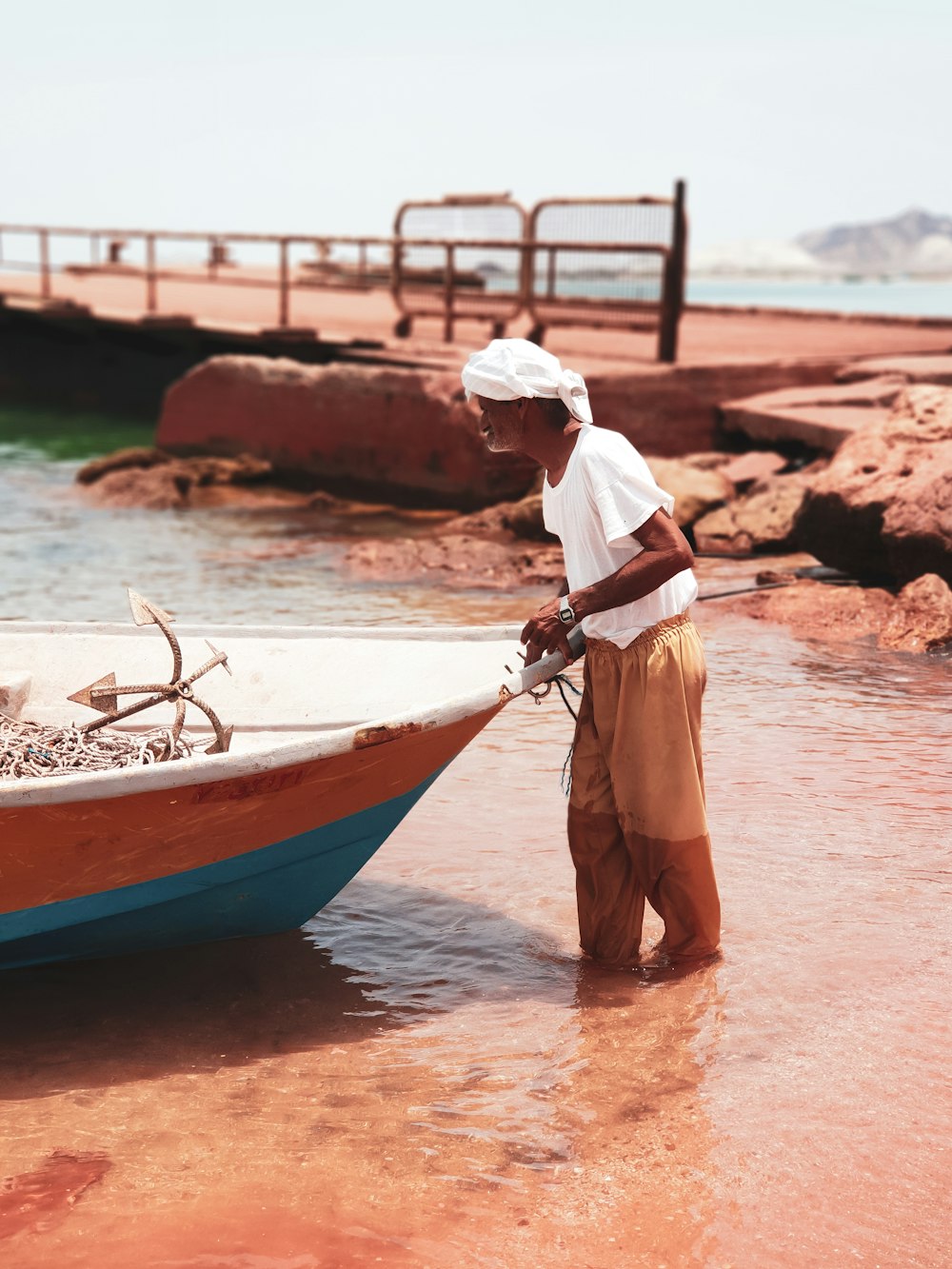 man in white shirt standing beside red and blue boat