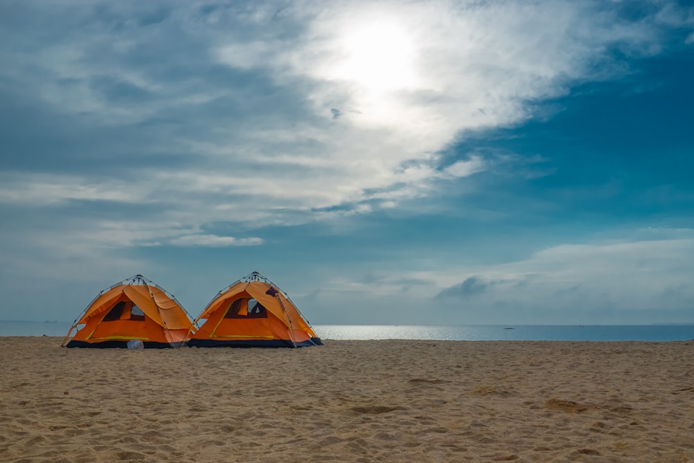 two orange and black tent at a beach