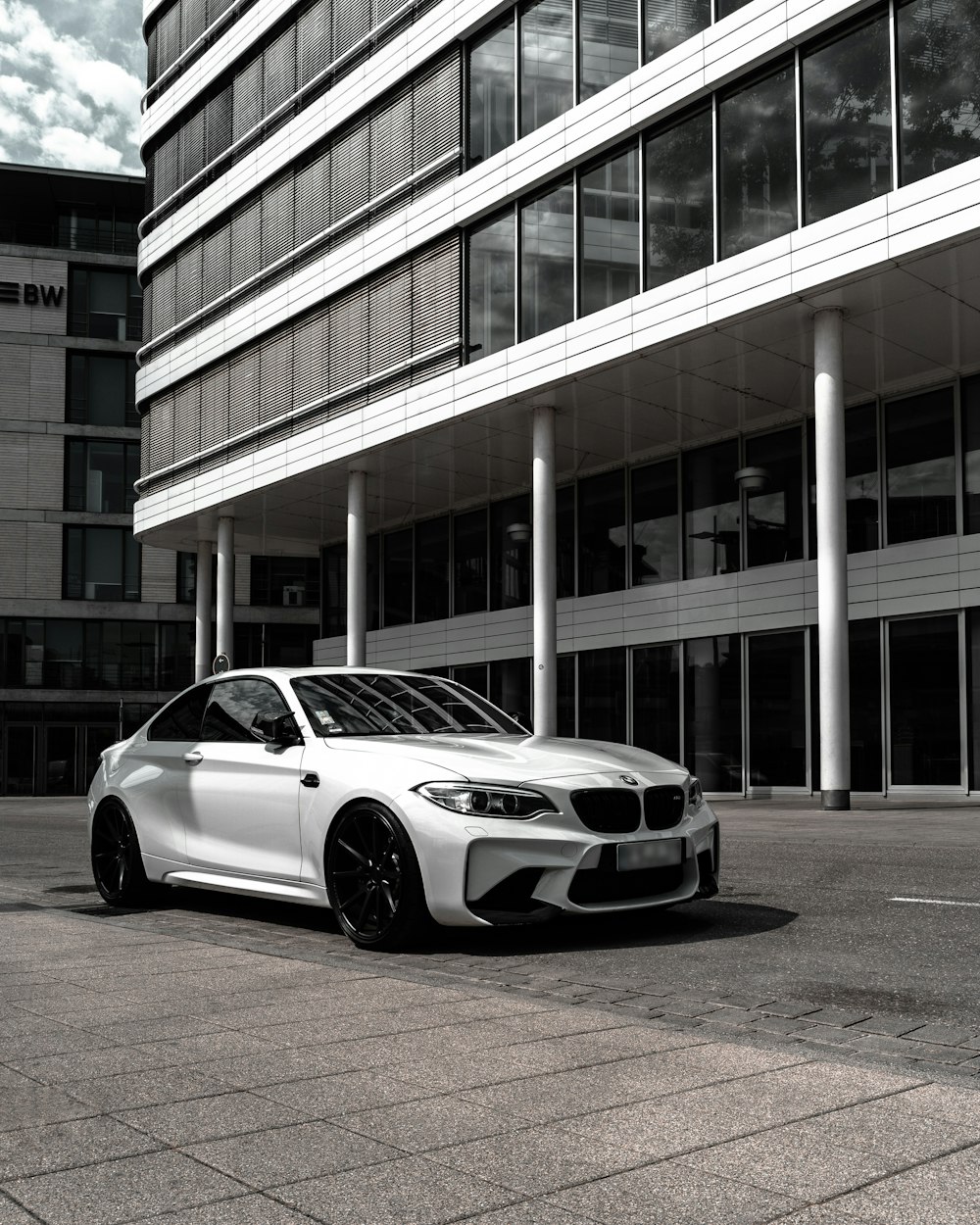 grayscale photography of BMW coupe in front of building