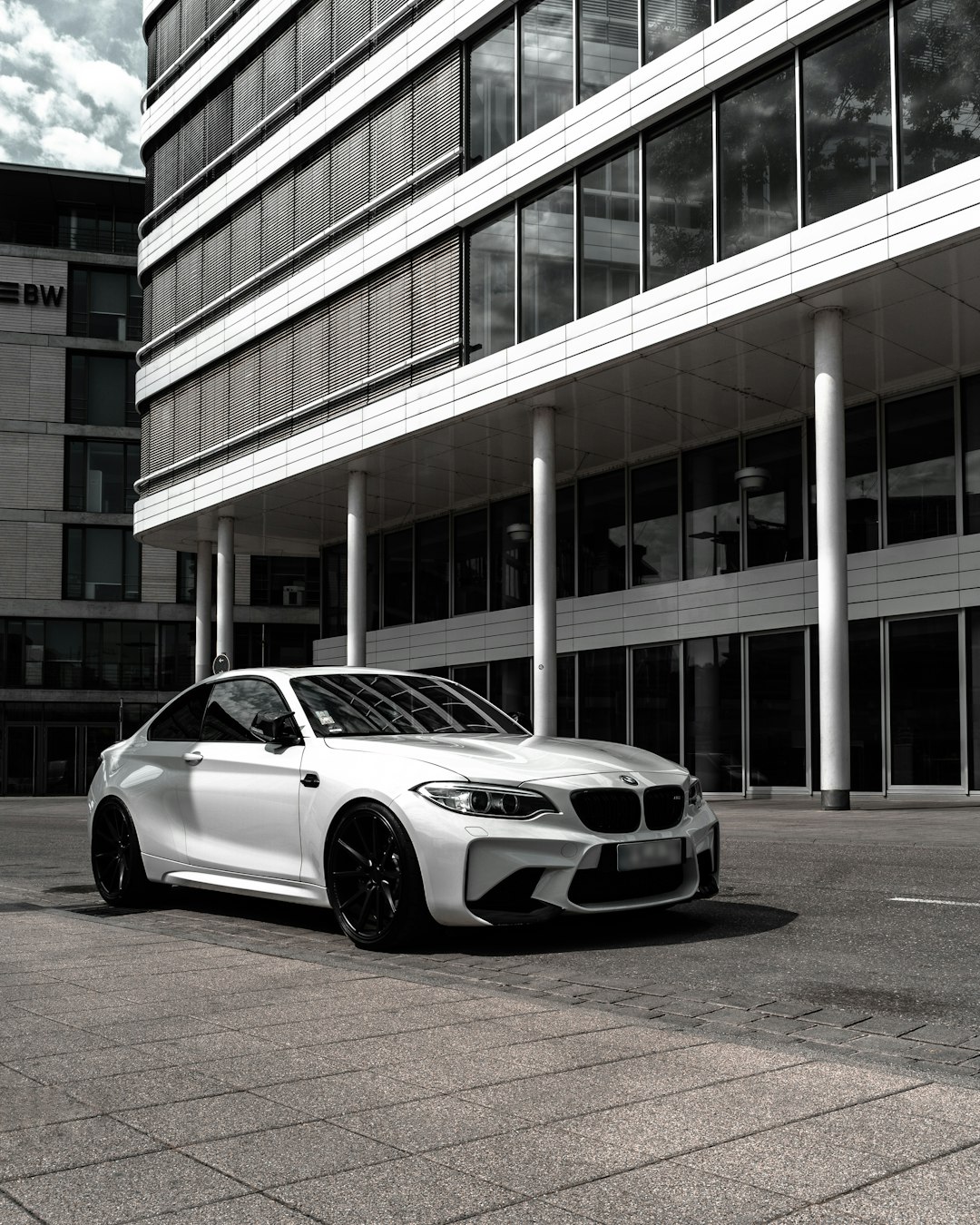 grayscale photography of BMW coupe in front of building