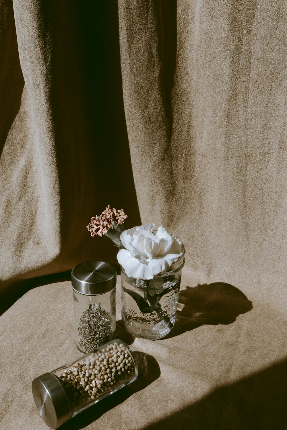 white petaled flowers and two clear glass condiment shakers