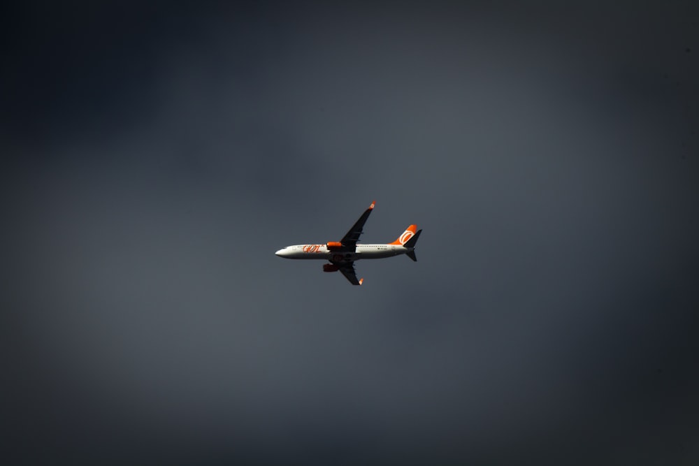 flying white and red plane under cloudy sky ]