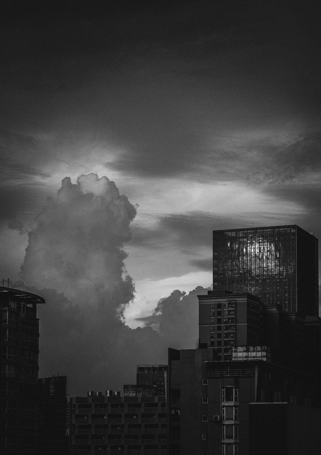 grayscale photography of high-rise buildings under cloudy sky