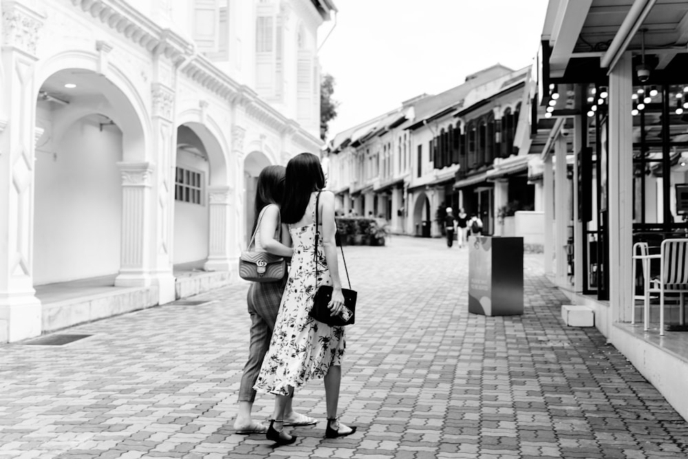 two women walking toward building during daytime