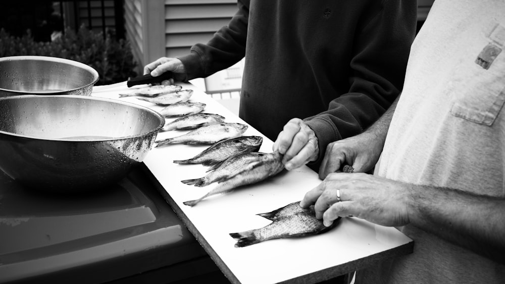 grayscale photography of two people in front of fish on table