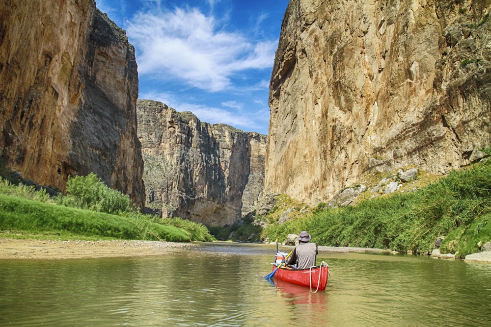 man in gray top sailing with red canoe boat during daytime