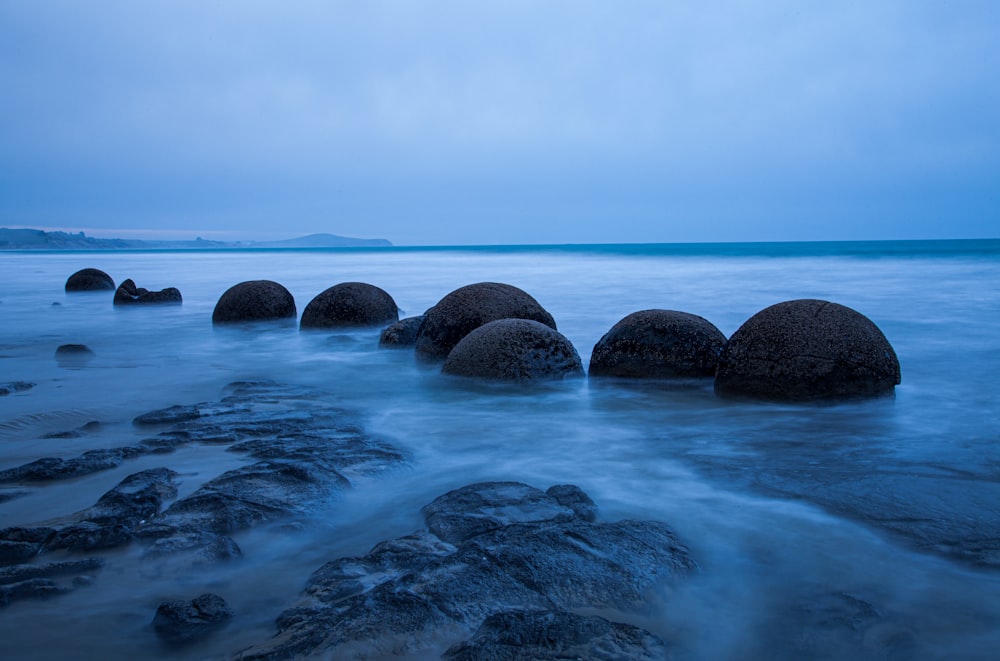 selective photography of rocks surrounded by body of water