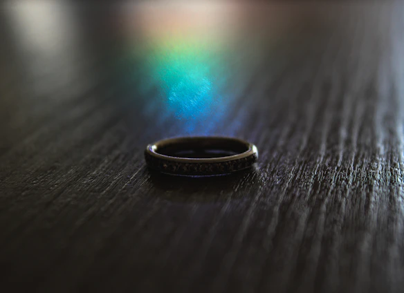 Close-up of a sleek silver ring resting on a textured black leather surface, reflecting soft urban light.