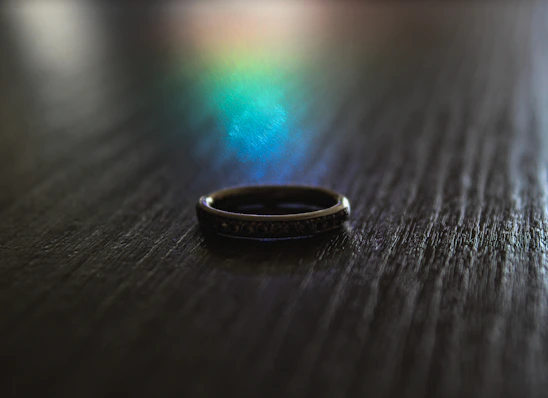 Close-up of a sleek silver ring resting on a textured concrete surface, reflecting soft natural light.