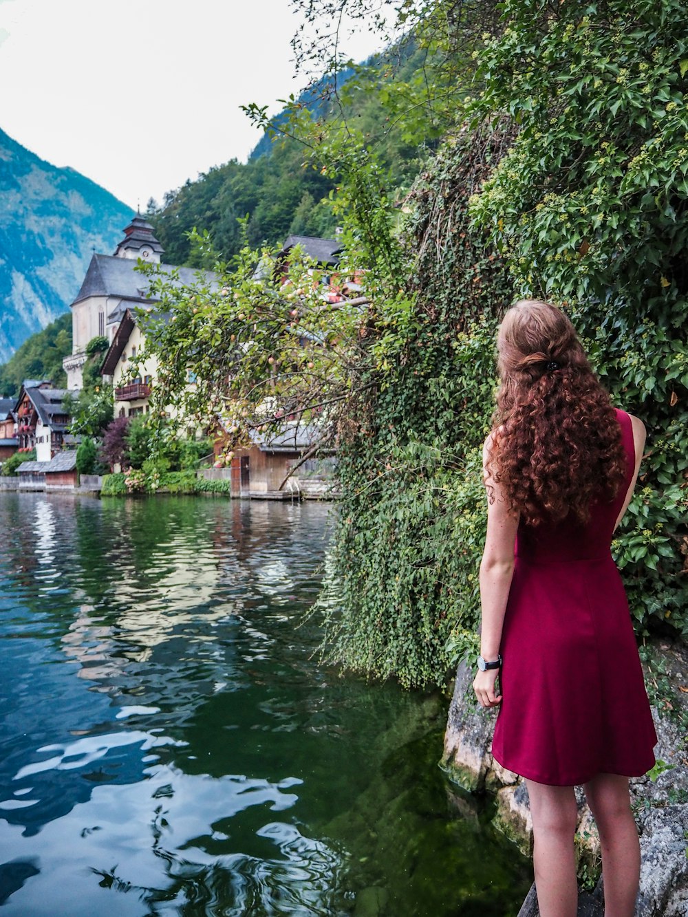 woman in maroon sleeveless dress near body of water during daytime