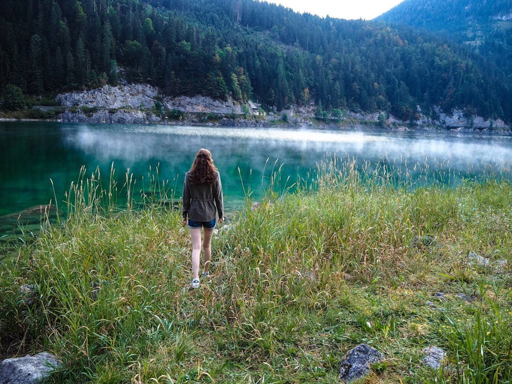 woman walking on green grass near body of water