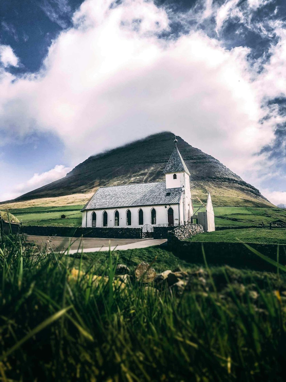 white and gray house in green field viewing mountain under white and blue skies