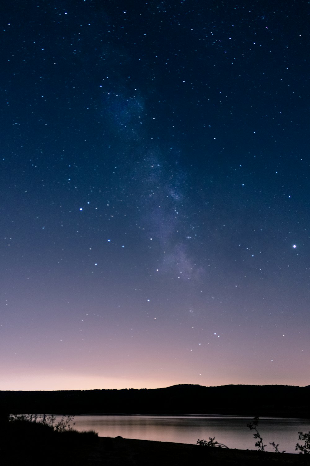 the night sky with stars above a lake