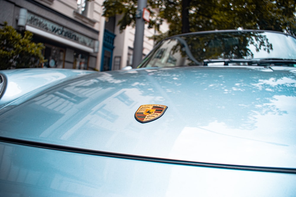 gray Porsche convertible car parked beside green tree during daytime ]