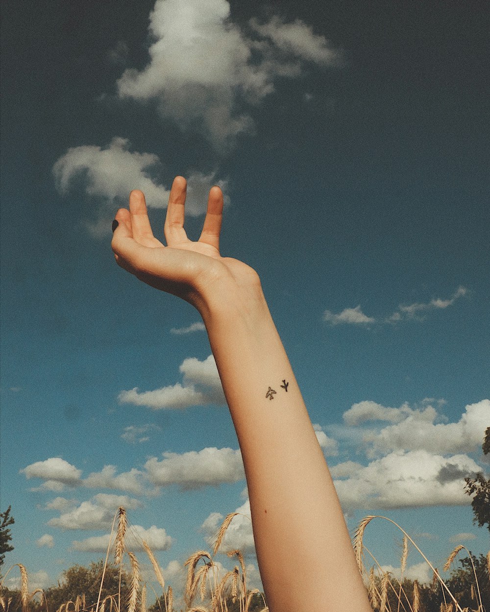 Person streckt die linke Hand zum Himmel aus