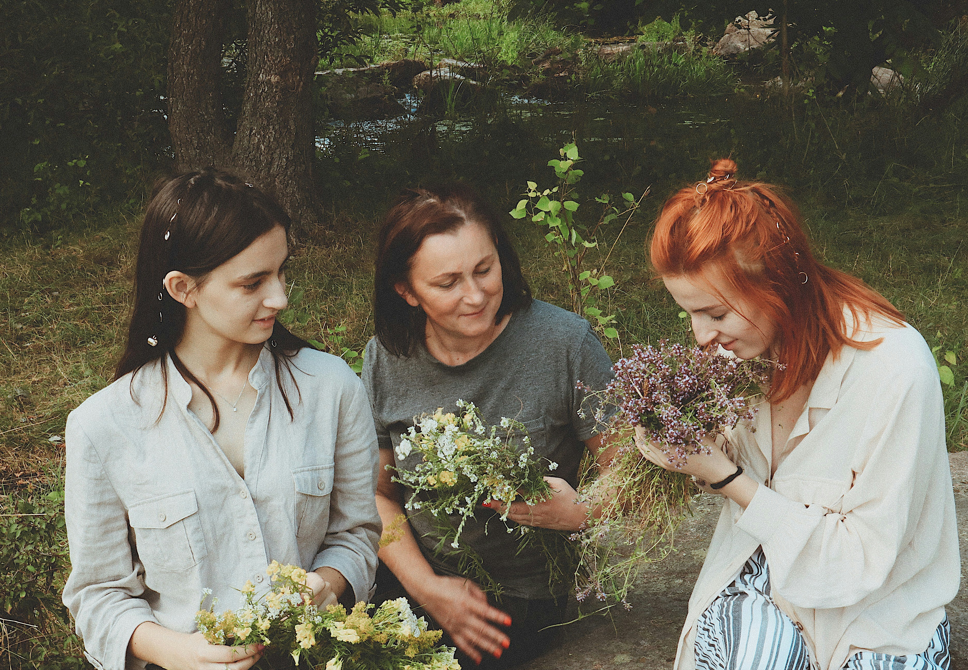 three women holding bouquet of flowers while one of them sniffing the flowers