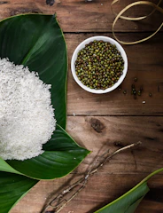 Bright green moong dal grains spread on a rustic wooden table.