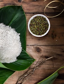 Soybeans in a wooden bowl with fresh green leaves, highlighting natural ingredients.