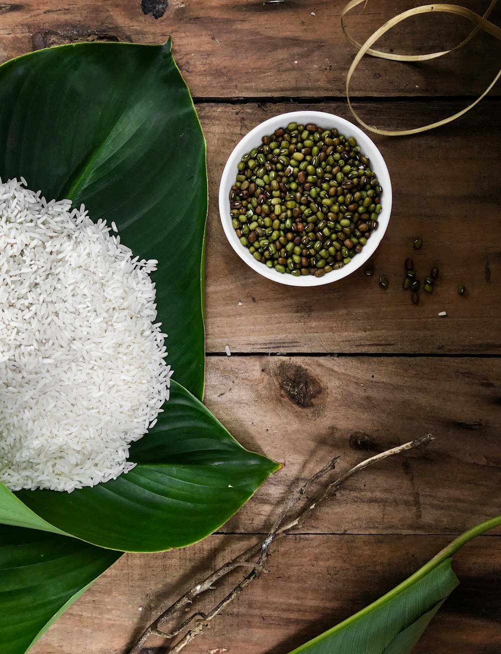 rice in green leaf beside bowl of seeds