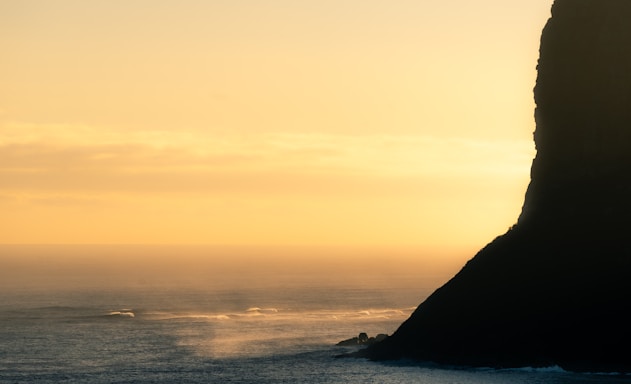 A serene view of the cliffside resort overlooking the calm sea at sunset.