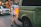 A customer shaking hands with a mechanic beside a service van in a busy city street.