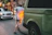A customer shaking hands with a mechanic beside a service van in a busy city street.