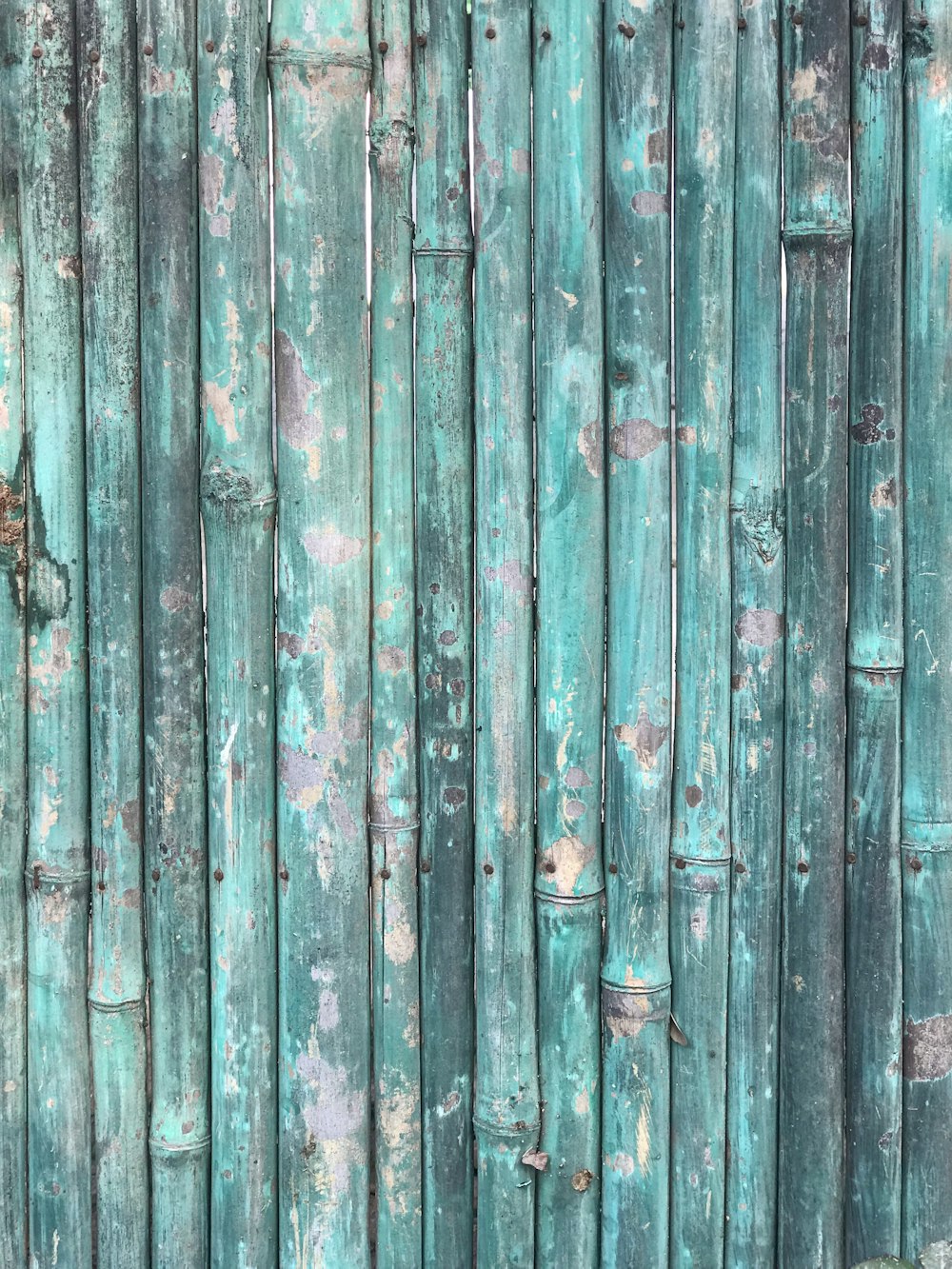 a close up of a bamboo fence with peeling paint