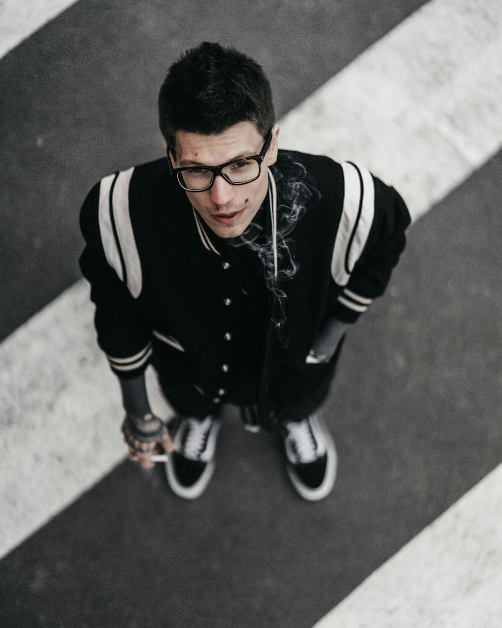 aerial photo of man wearing jacket standing on pedestrian lane and looking up