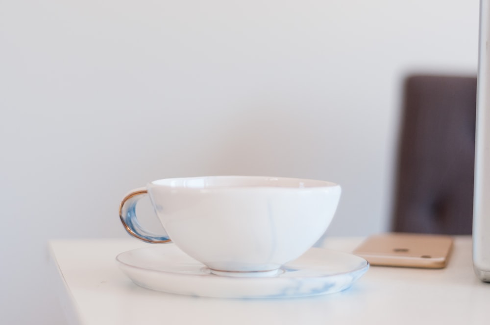 a white cup and saucer on a white table