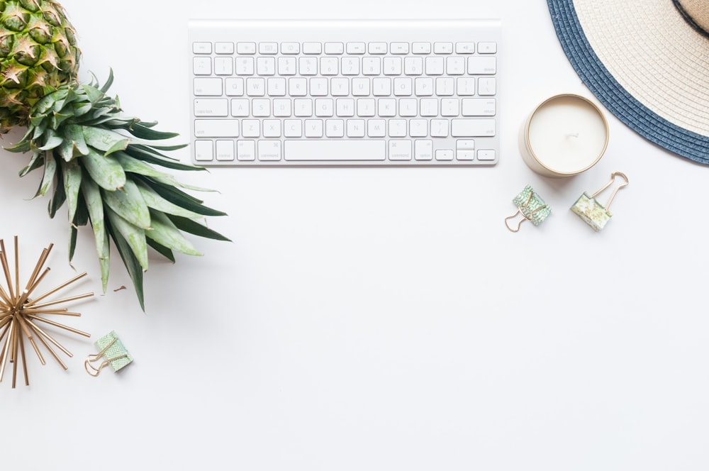 a pineapple next to a keyboard and a cup of coffee