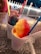 Colorful shaved ice treats in white cups, each with a different vibrant hue and a straw sticking out. The background displays a white picket fence and an outdoor setting, creating a casual snack atmosphere.
