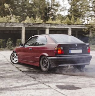 The e30 m62tub44 car sliding sideways on a wet track with sparks flying.