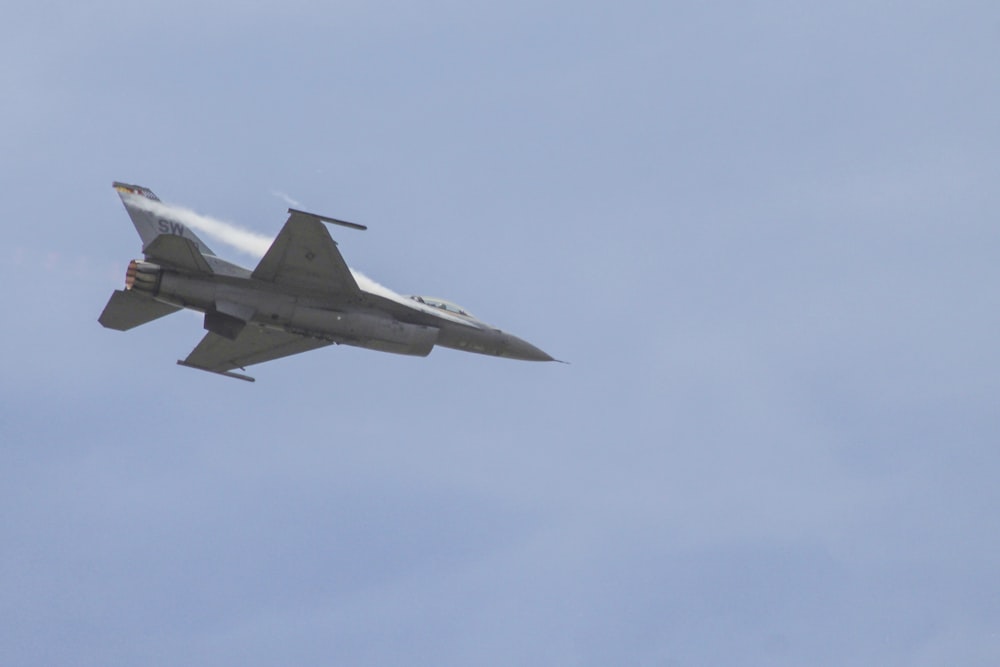 gray fighting plane flying on the sky