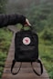 person holding black and red leather backpack
