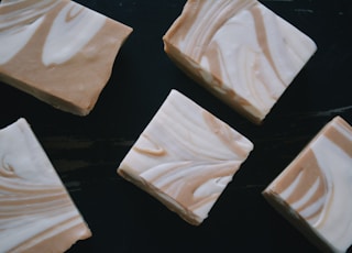 four pieces of white chocolate sitting on top of a black surface