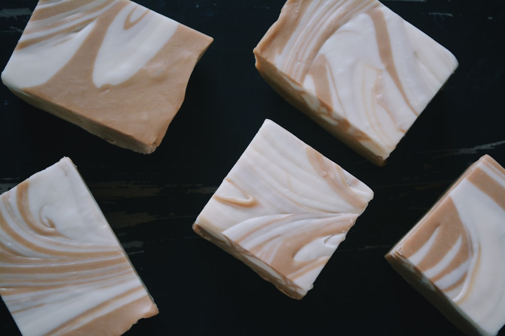 four pieces of white chocolate sitting on top of a black surface