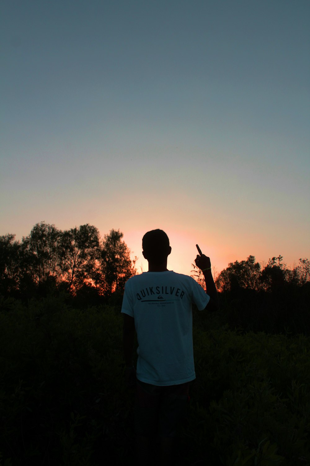 man standing on grass field under orange sky