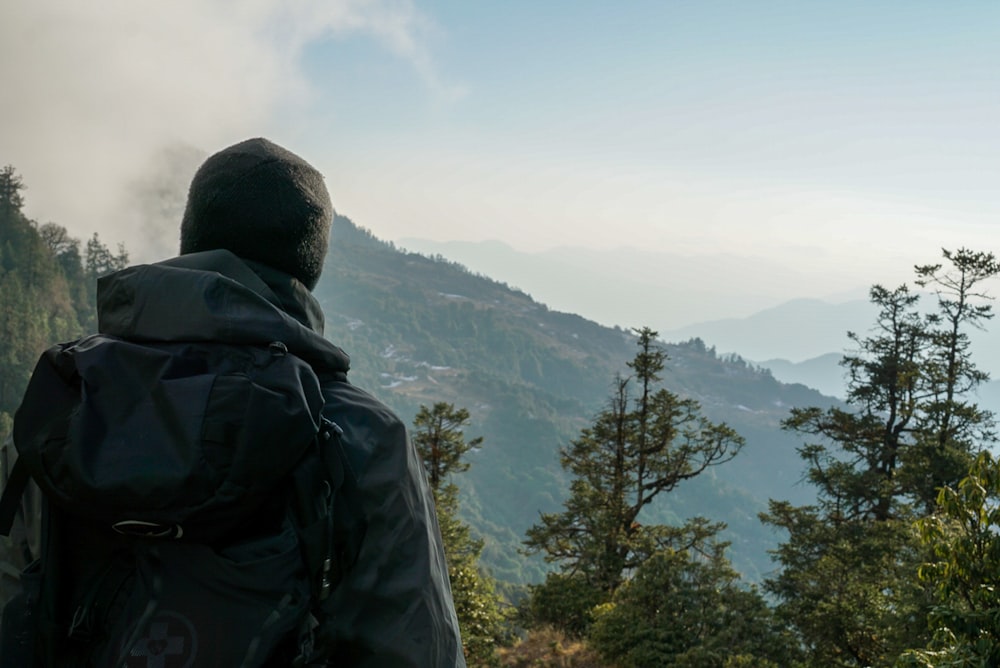 man standing near forest viewing mountain