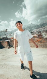 A confident young person wearing White Luhaif cargo pants, standing on an urban rooftop at sunset, embodying strength and modern street luxury.