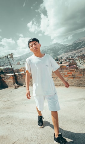 A confident young person wearing White Luhaif cargo pants, standing on an urban rooftop at sunset, embodying strength and modern street luxury.