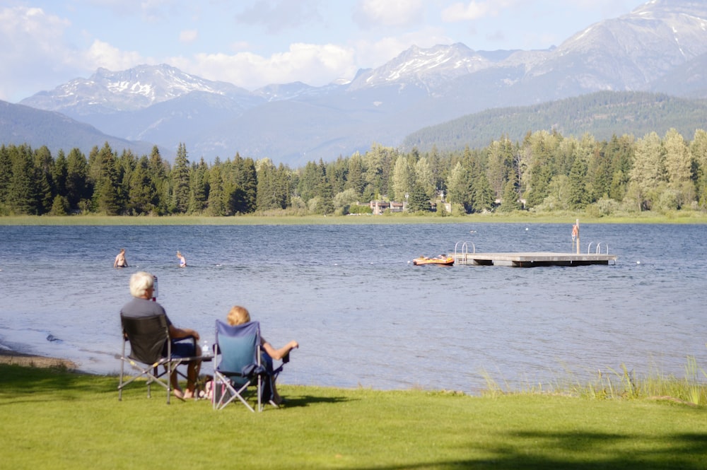 due persone sedute sull'erba di fronte al lago